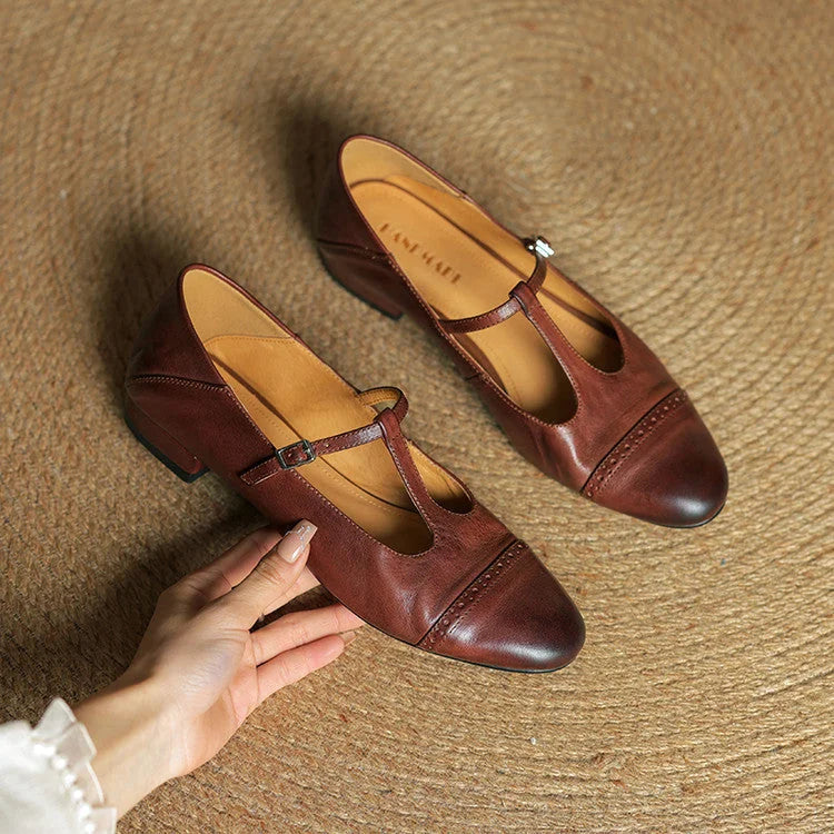 Brown Women's T-Strap Mary Leather Flats — Hannah Buckle Cap-Toe - Flat Lay Hand Holding